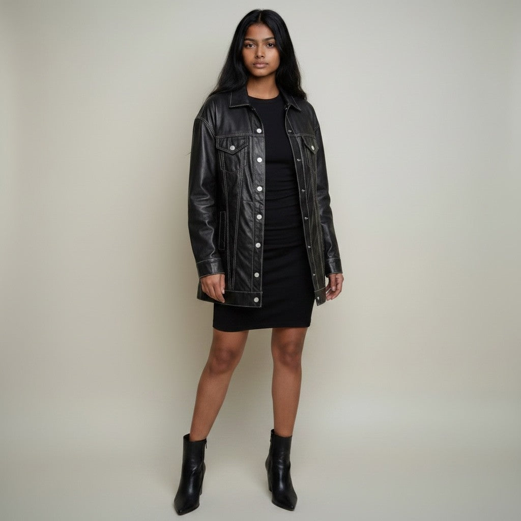 Jolie Jordan Boutique black faux leather longline trucker jacket with white stitching, oversized fit, button front, worn by a model.
