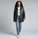 Jolie Jordan Boutique black faux leather longline trucker jacket with white stitching, worn by a model with jeans.